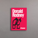 Book cover with 'Donald Rodney: A Reader' and a black silhouette of a burning house on a pink background.